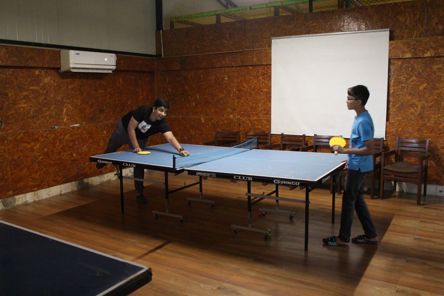 Two boys playing a game of table tennis in an indoor recreational room