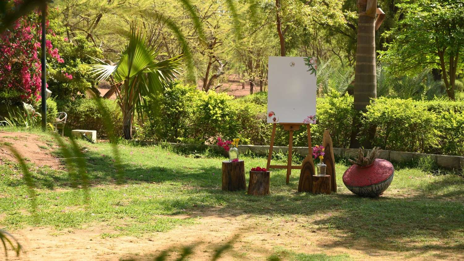 Decorated welcome board on an easel placed in a garden area with flowers and natural greenery.