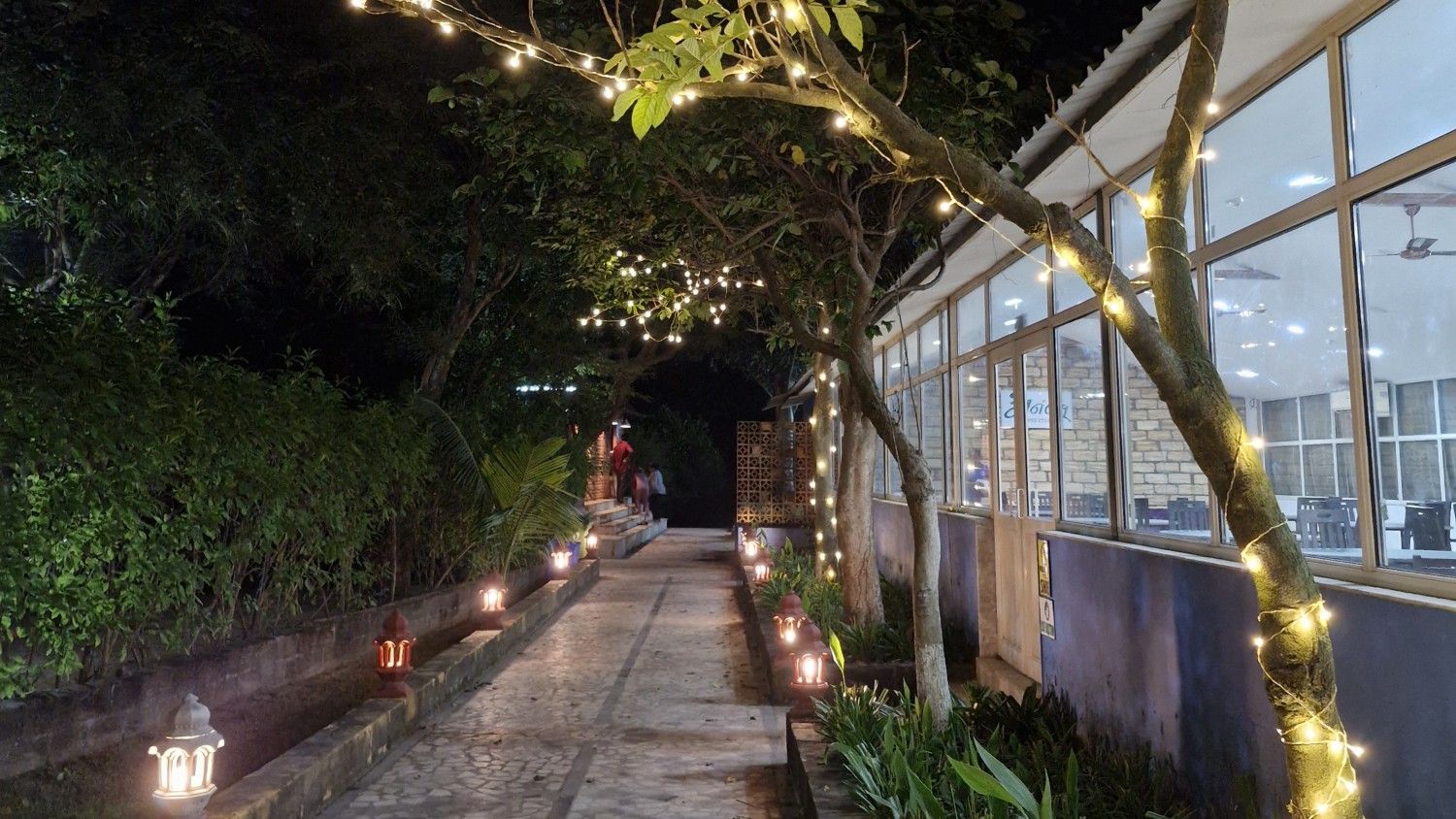 Charming whitewashed cottage with a thatched roof surrounded by flowering plants and wooden deck