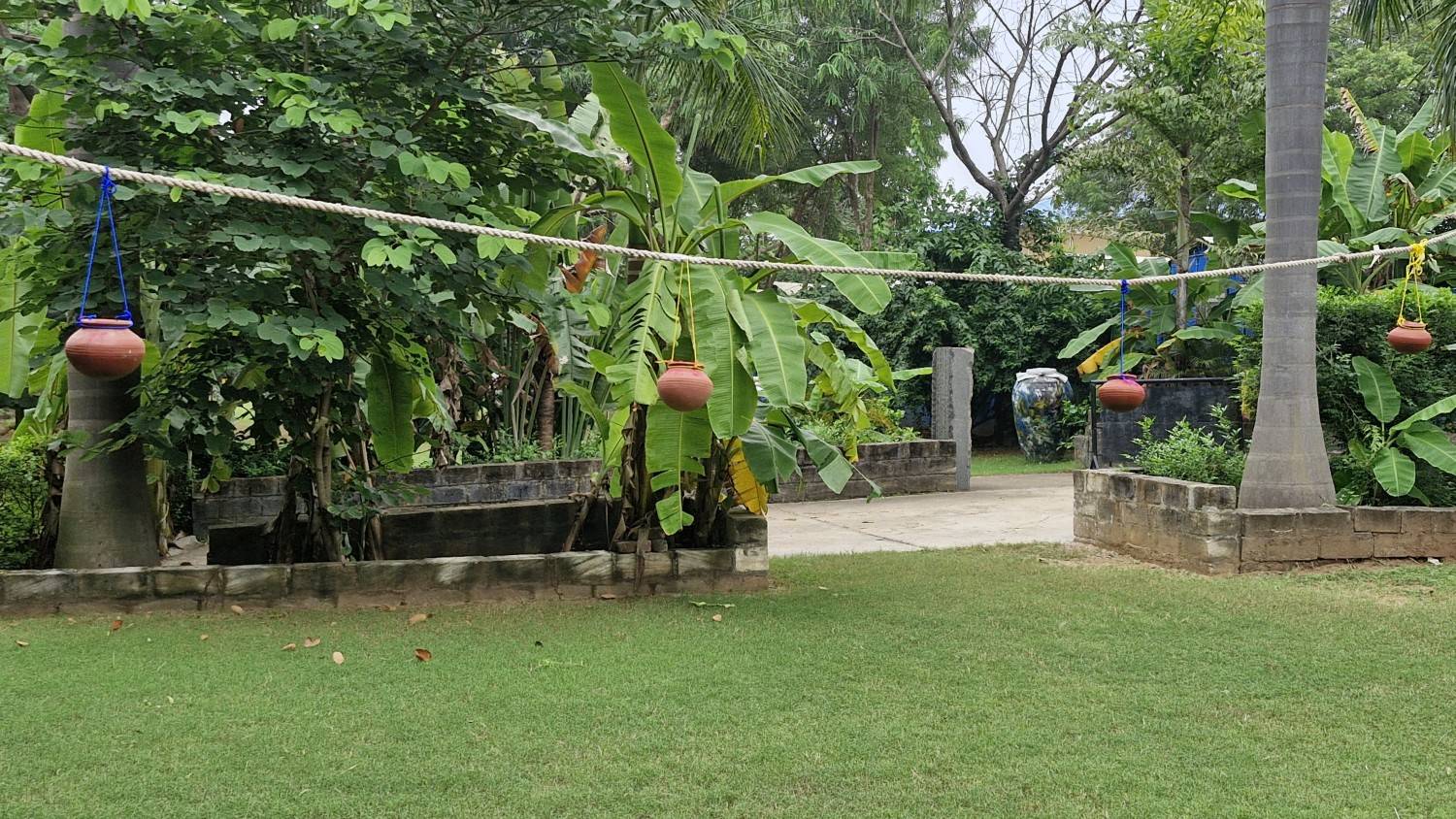 Private garden with wooden chairs and hammock surrounded by colorful flowers and shady trees