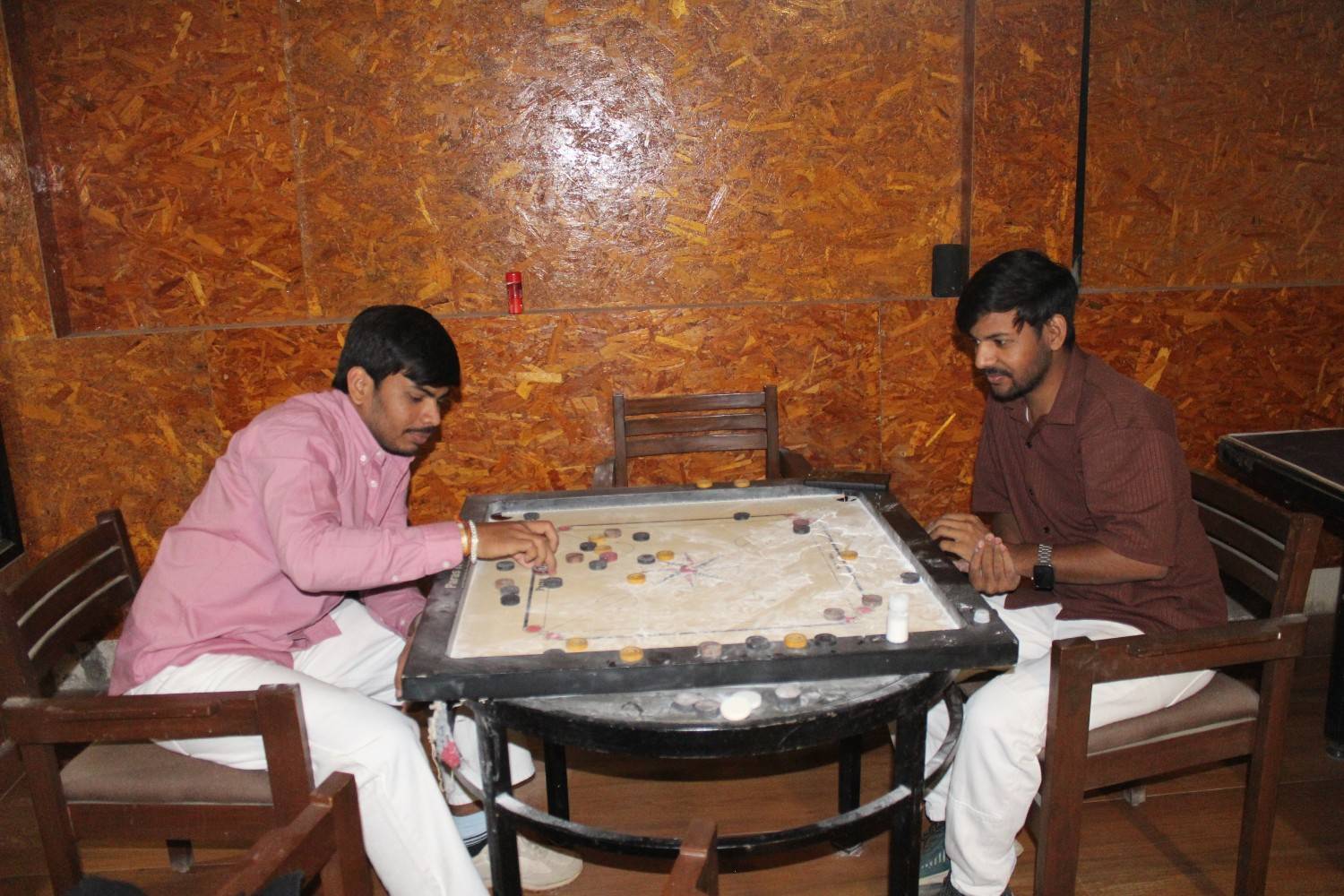 Two employees playing a focused game of carrom during office retreat
