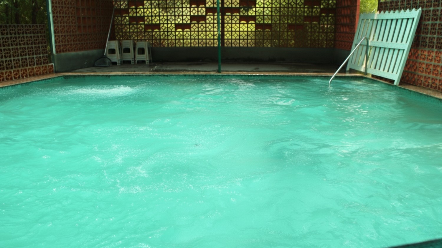 Private garden with wooden chairs and hammock surrounded by colorful flowers and shady trees