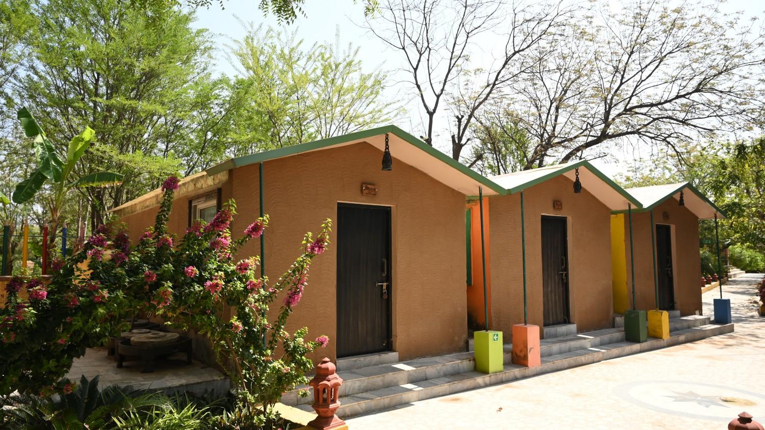Charming whitewashed cottage with a thatched roof surrounded by flowering plants and wooden deck