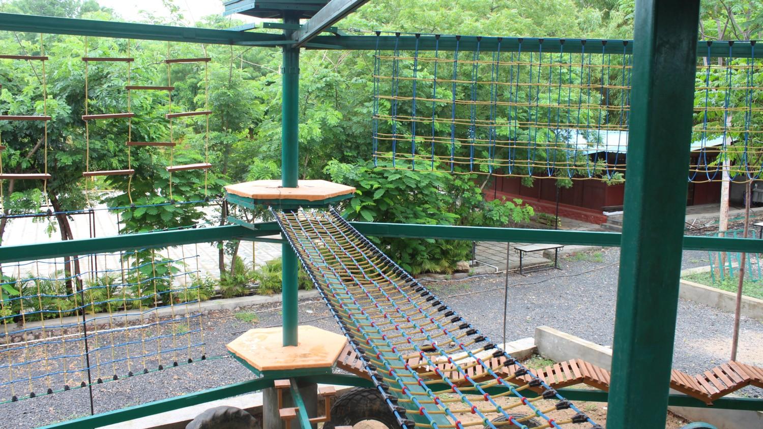 Private garden with wooden chairs and hammock surrounded by colorful flowers and shady trees