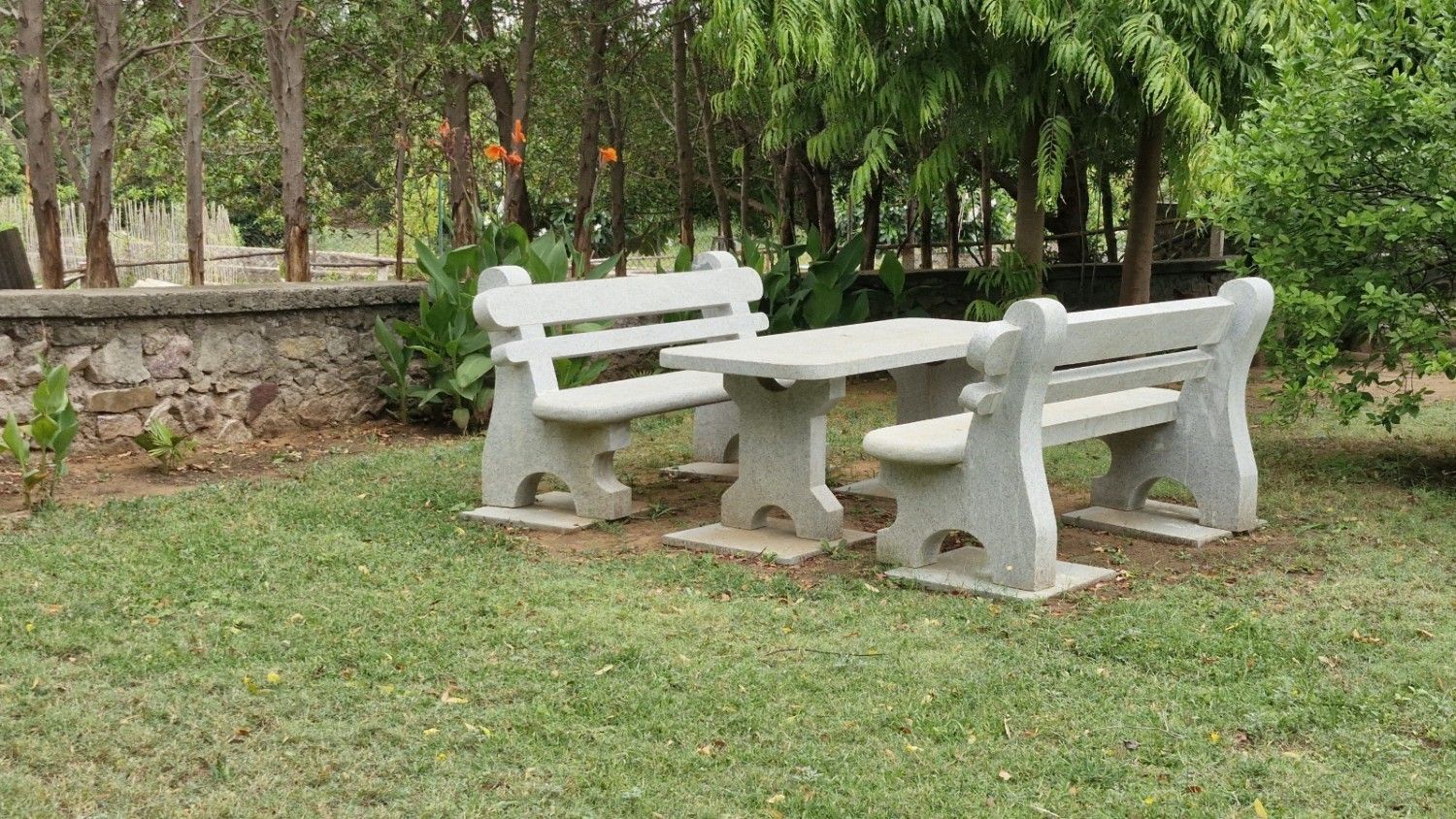 Private garden with wooden chairs and hammock surrounded by colorful flowers and shady trees