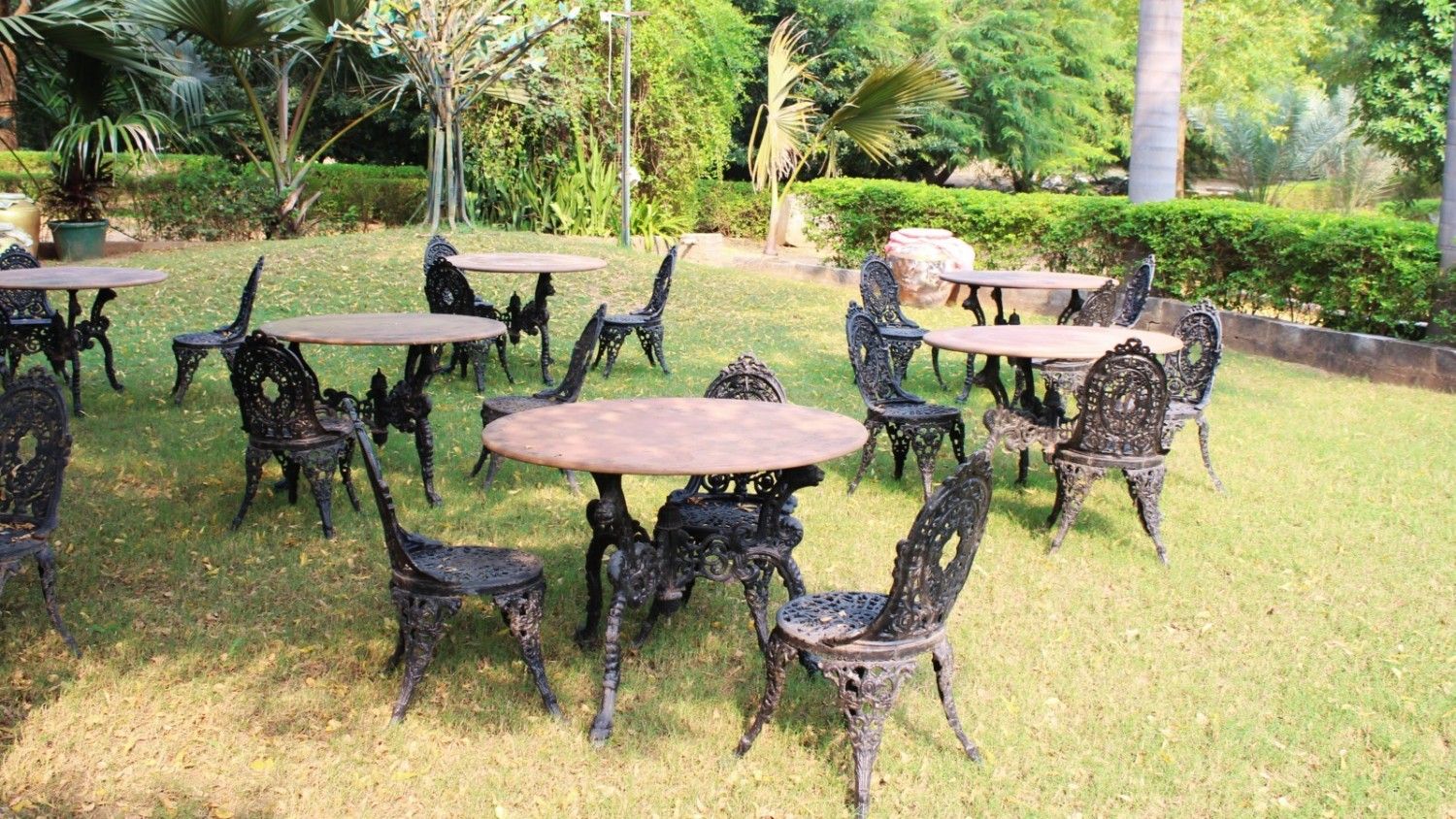 Private garden with wooden chairs and hammock surrounded by colorful flowers and shady trees